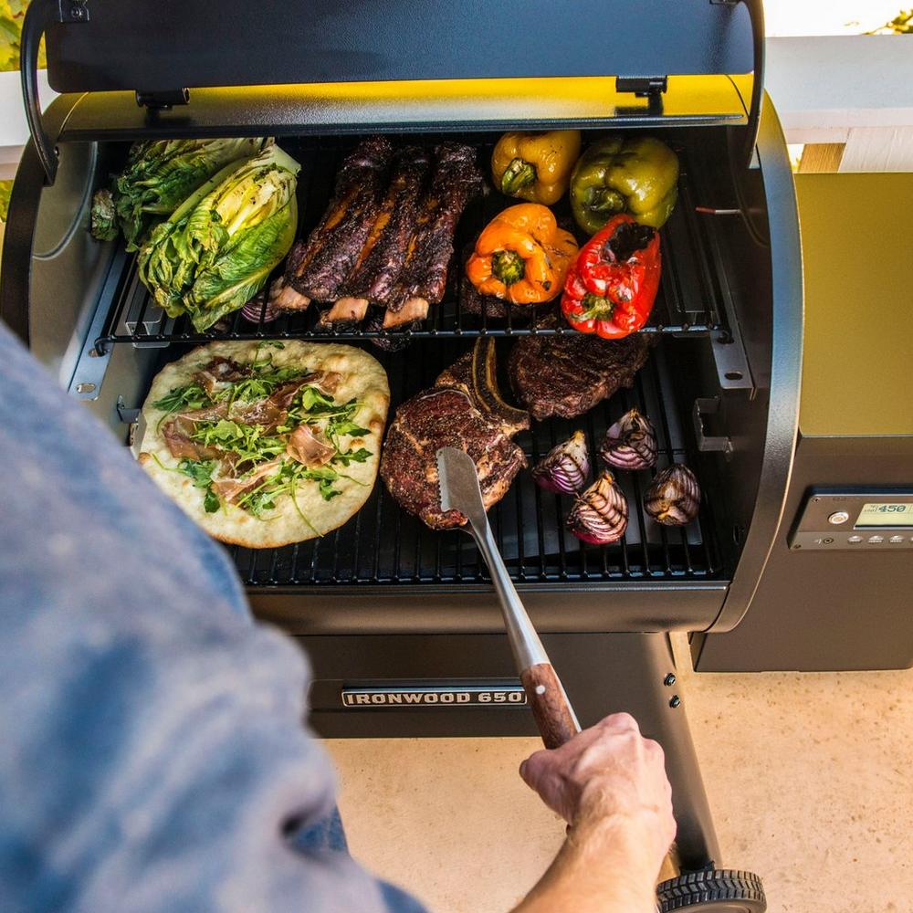 Traeger Ironwood 650 Pellet Grill Lifestyle with some Steaks, Pizza, Red Peppers