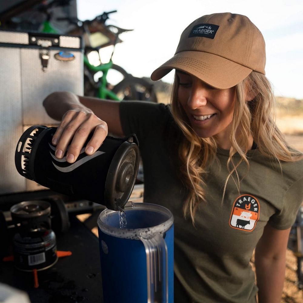 Traeger Dad Cap Beige Lifestyle Worn by a Woman Pouring Water