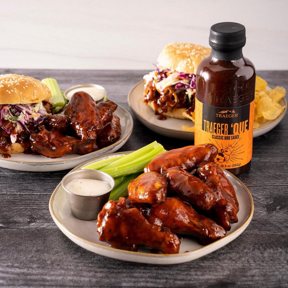 Traeger 'Que BBQ Sauce Lifestyle on the Table with Chicken and Burgers